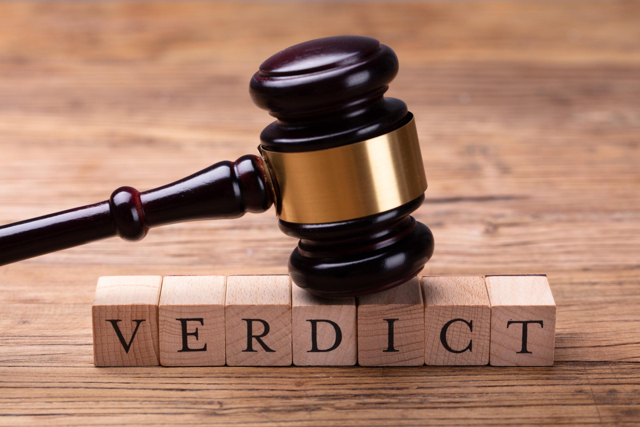 A gavel laid atop wooden blocks with letters on the front that spell out 'verdict'