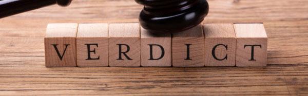 A gavel laid atop wooden blocks with letters on the front that spell out 'verdict'