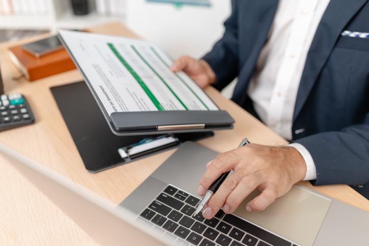 A businessman in a suit analyzing financial charts and performance reports in a bright modern office, focusing on strategy, data, and budget planning for company growth and long-term success.