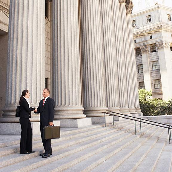 Two people shaking hands in front of the courthouse