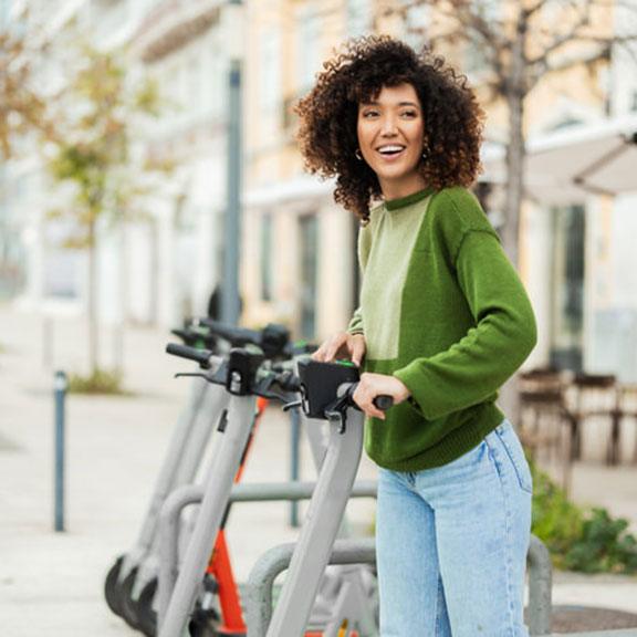 Happy adult woman using shared e-scooter for urban transport Happy adult woman using shared e-scooter for urban transport