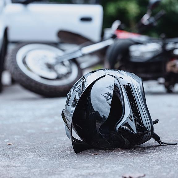 motorcycle-accidents-01 A motorcycle helmet rests on the ground beside a parked car, indicating a recent ride or potential accident.