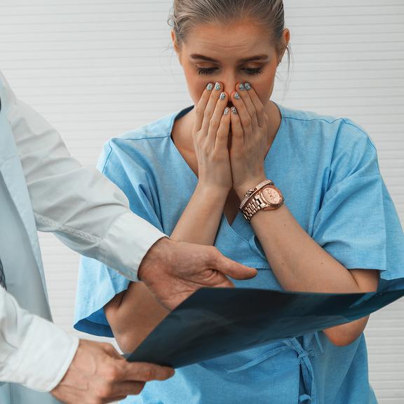 A shocked patient covering her face.
