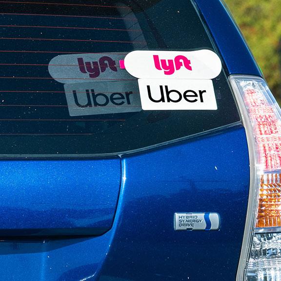 A back of a car with Uber and Lyft stickers. A back of a car with Uber and Lyft stickers.